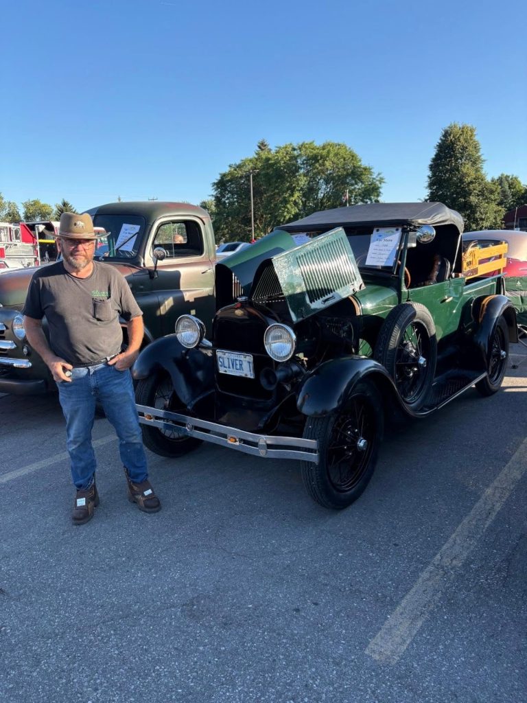 An owner stands beside his green Ford Model A at the car show