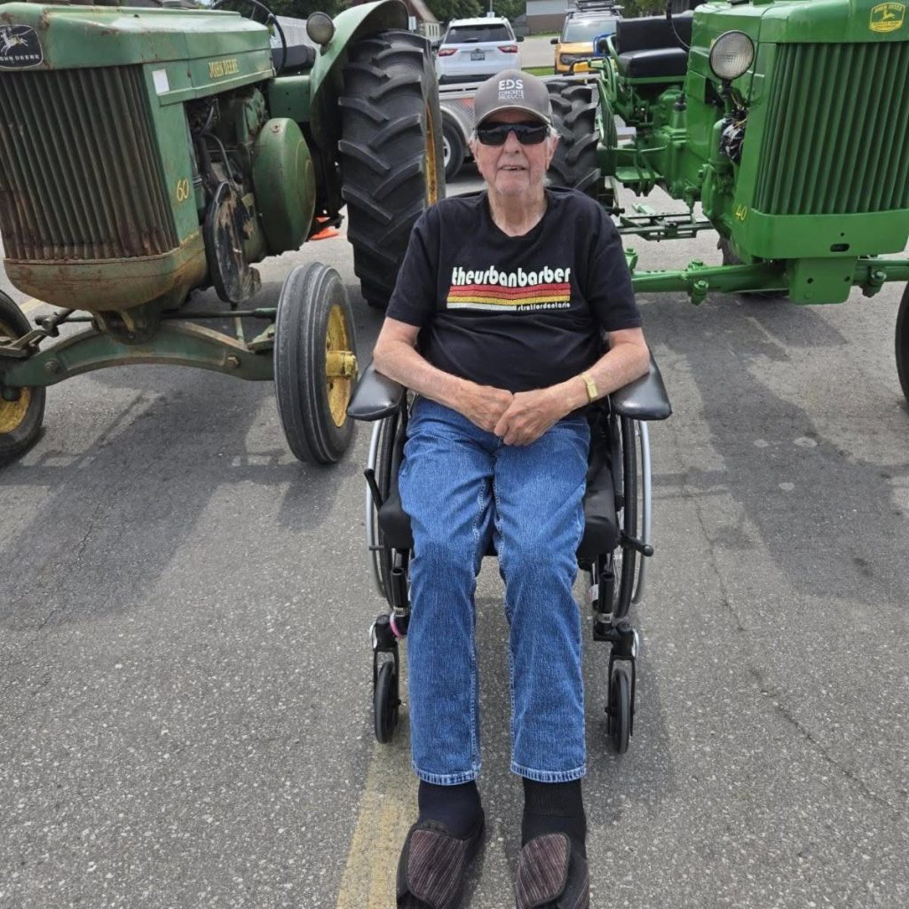 A resident seated between two vintage John Deere tractors