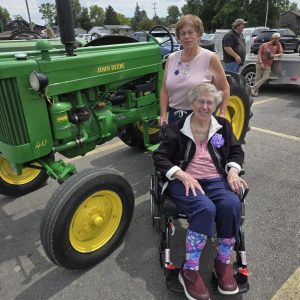 A resident and a staff member beside a restored John Deere 40